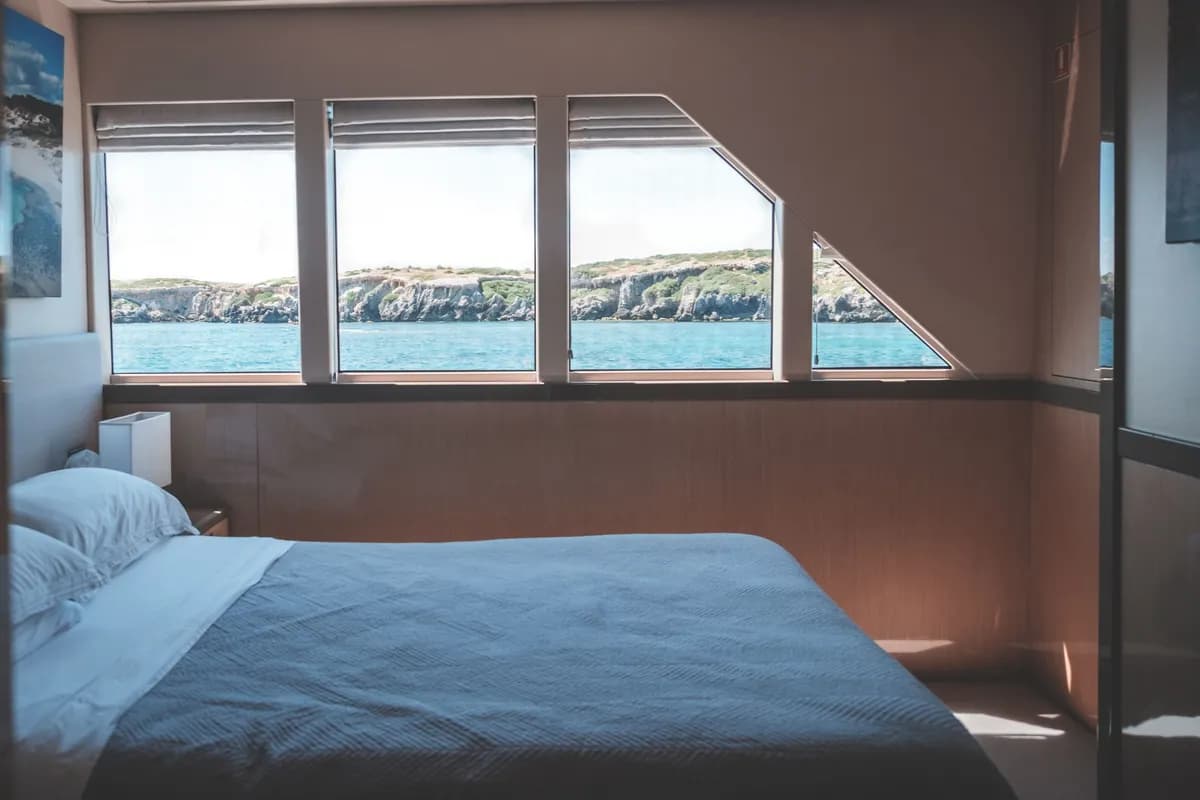 BookNoFees exempelbild: Ljus båtkabin med säng och stora fönster mot havet