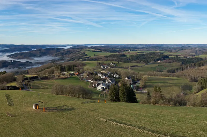 Wildewiese i Sauerlands berg, med en skidlift på ängen och byn nedanför