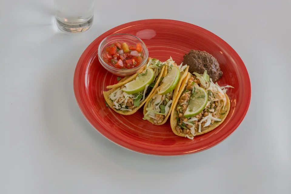 BookNoFees: Exempelbild: Tre tacos toppade med limeskivor och salsa på en röd tallrik
