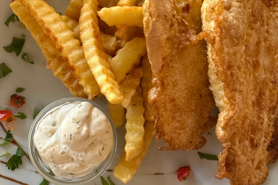 BookNoFees: Exempelbild: Panerade fiskfiléer med vågiga pommes frites och en liten skål med sås